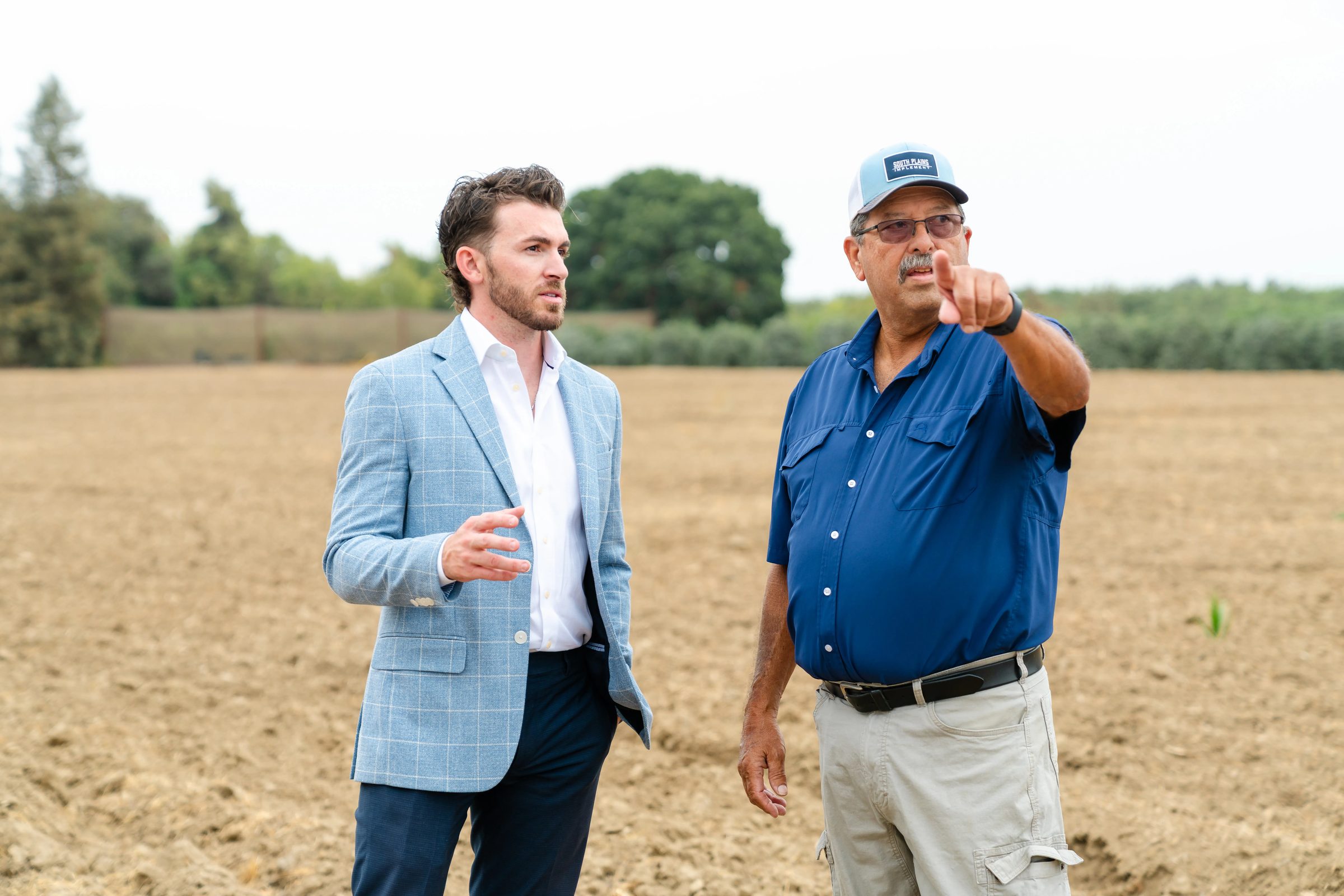 Central Valley farmer pointing across a field while talking with an adviser