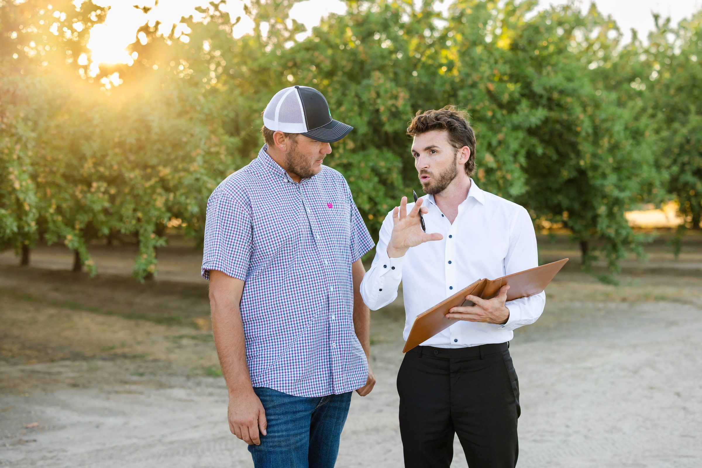 Adviser walking a Central Valley farmer through planning documents at sunset